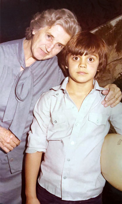 Descrição de imagem: fotografia colorida. Dois homens e um garoto em pé, fotografia tirada à luz do dia, em local com árvores. Na frente e em destaque estão João Pedro e Seu Paulino, filho e pai de Rodrigo, respectivamente. João Pedro é um garoto de pele branca e cabelo castanho claro, ele usa camiseta cinza com grafismos cinza escuro. Seu Paulino é um homem de pele branca e cabelo grisalho, ele usa chapéu branco, camisa azul e calça jeans. Rodrigo está ao fundo, ele sorri. Usa chapéu bege, camiseta marrom e calça jeans escura. Fim da descrição.